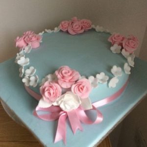 onr teir cake in pastel blue with delicate white and pink roses finished with a pink ribbon