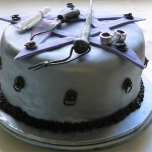 purple cake with 5 pointed star and handcuff and whip details, side view