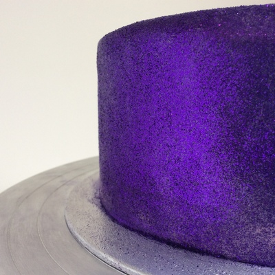 close up of one side of a cake covered in solid purple glitter