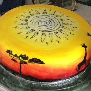 African sunset cake, sunset colours around the edge with African animals and trees in silhouette and sun design on top