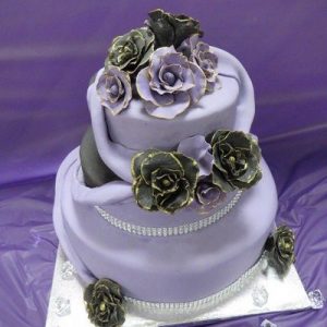 3 tier wedding cake in black and purple with purple swags and purple and black gold edged roses purple side
