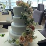4 tier white wedding cake with fresh flower sweeping down from the top layer